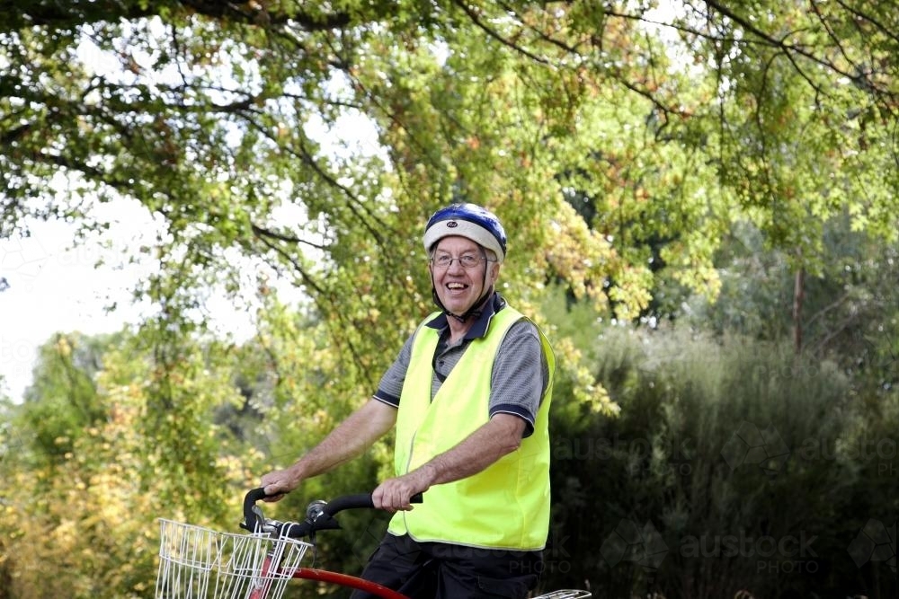 Man with disability in high visibilty vest riding bike - Australian Stock Image