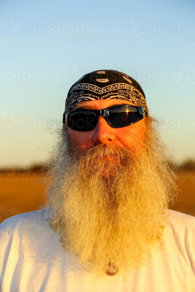 Man with full beard, sunglasses, and bandana head scarf. - Australian Stock Image
