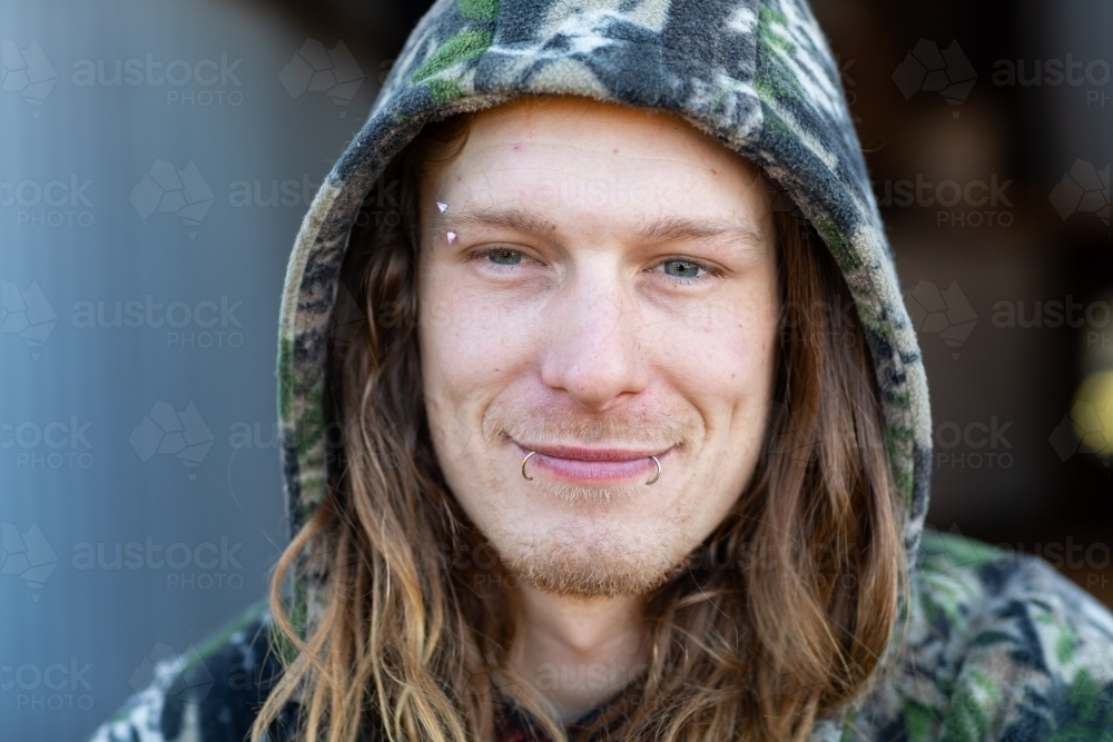 man with long hair in a hoodie face towards camera - Australian Stock Image