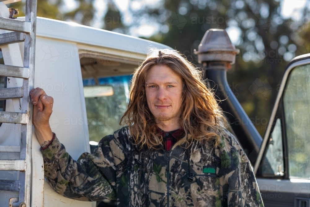 man with long hair leaning on ute - Australian Stock Image