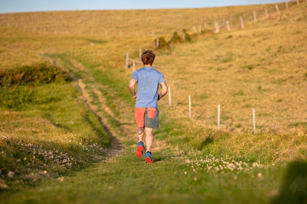Man with Tattoo Running in Countryside - Australian Stock Image