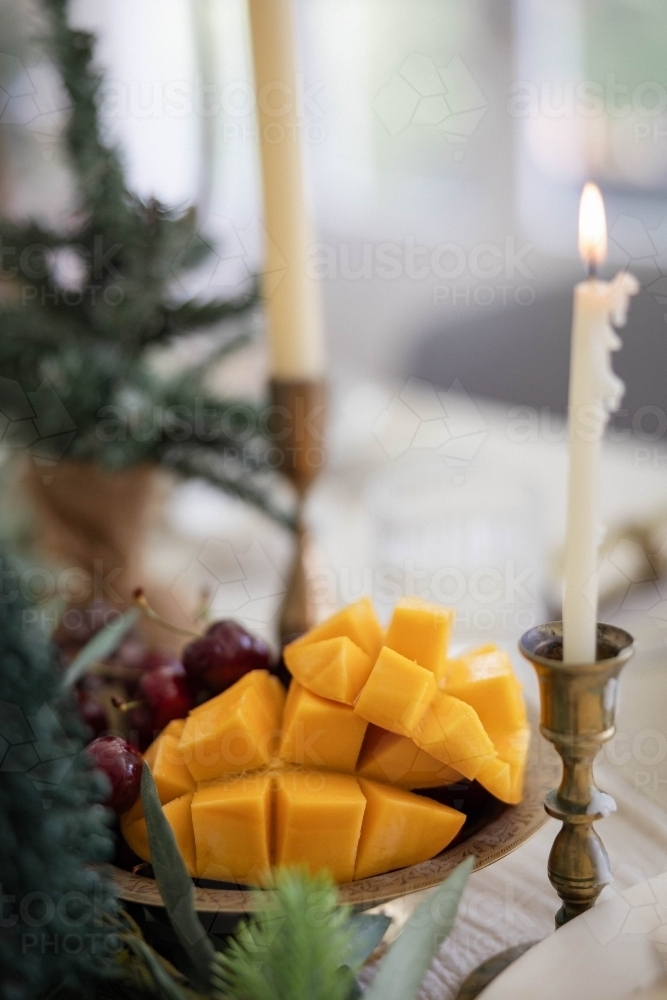 Mango and cherries in bowl on decorated Christmas table - Australian Stock Image