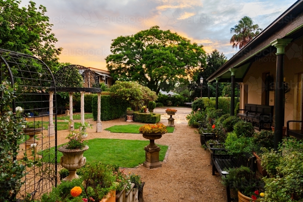 Manicured garden at sunset with plants in pots and pathways - Australian Stock Image