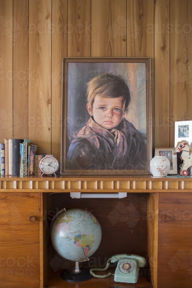 Mantle piece with crying boy painting and vintage decor - Australian Stock Image