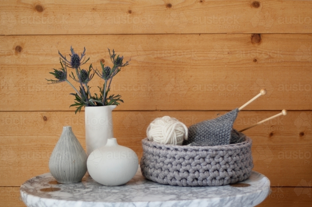 Marble coffee or bedside table with flowers, vases and knitting - Australian Stock Image