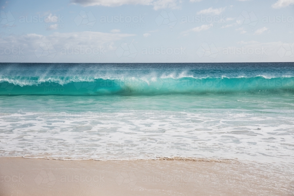 Mare's tail on waves breaking on beach - Australian Stock Image
