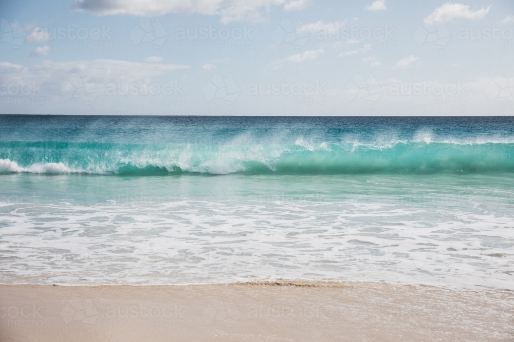 Mare's tail on waves breaking on beach - Australian Stock Image