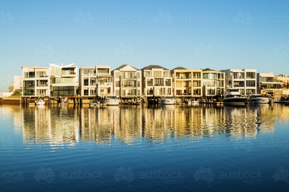 Marina homes reflecting in the water in morning light - Australian Stock Image