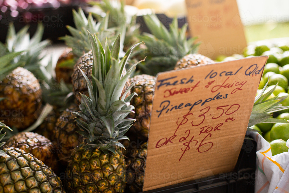 market pineapples next to a cardboard sign - Australian Stock Image