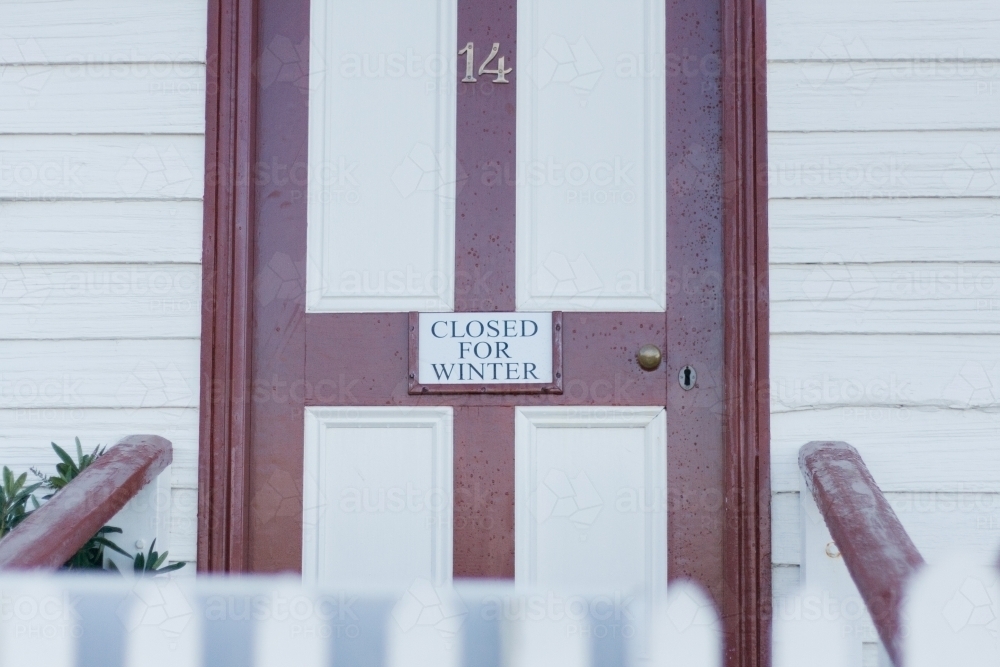 Maroon and white front door with 'Closed For Winter' sign - Australian Stock Image