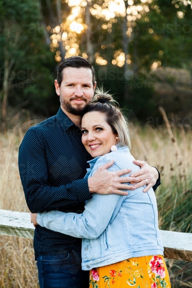 Married couple hug each other outside in park - Australian Stock Image