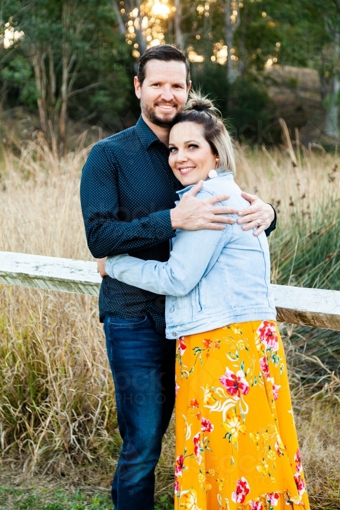 Married couple hug each other outside in park - Australian Stock Image