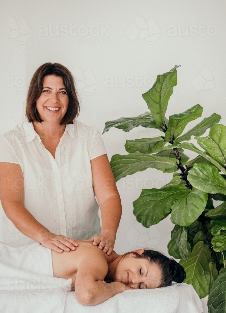 Masseuse looks happy as she works on a woman. - Australian Stock Image