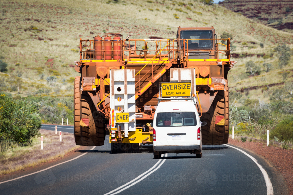 Massive mining truck escorted by pilot vehicle on a remote highway. - Australian Stock Image
