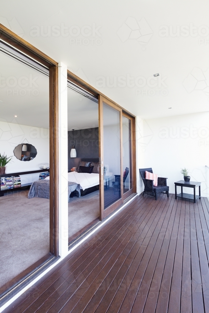 Master bedroom and large glass sliding doors to balcony in luxury Australian home - Australian Stock Image