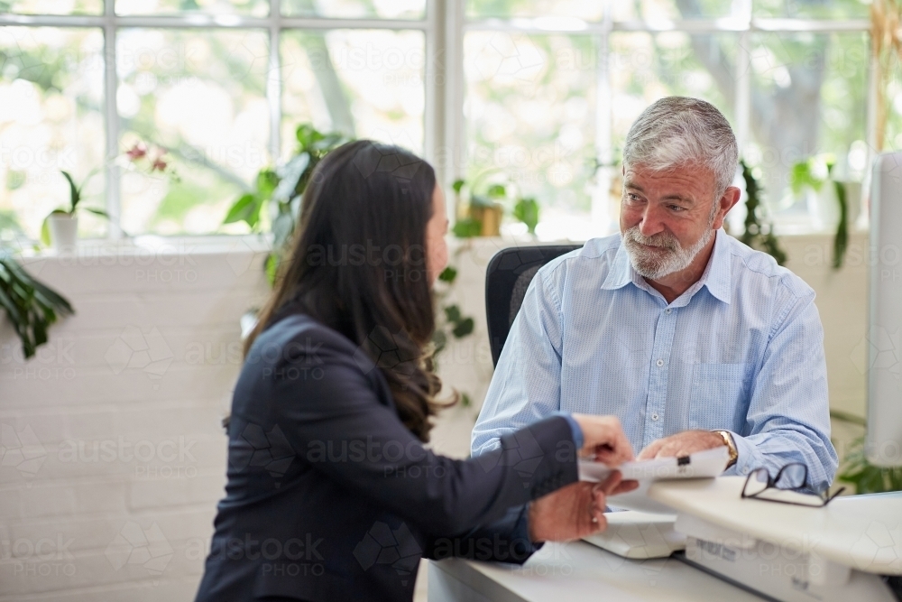 Mature aged male office worker meeting with a woman in a creative warehouse space - Australian Stock Image