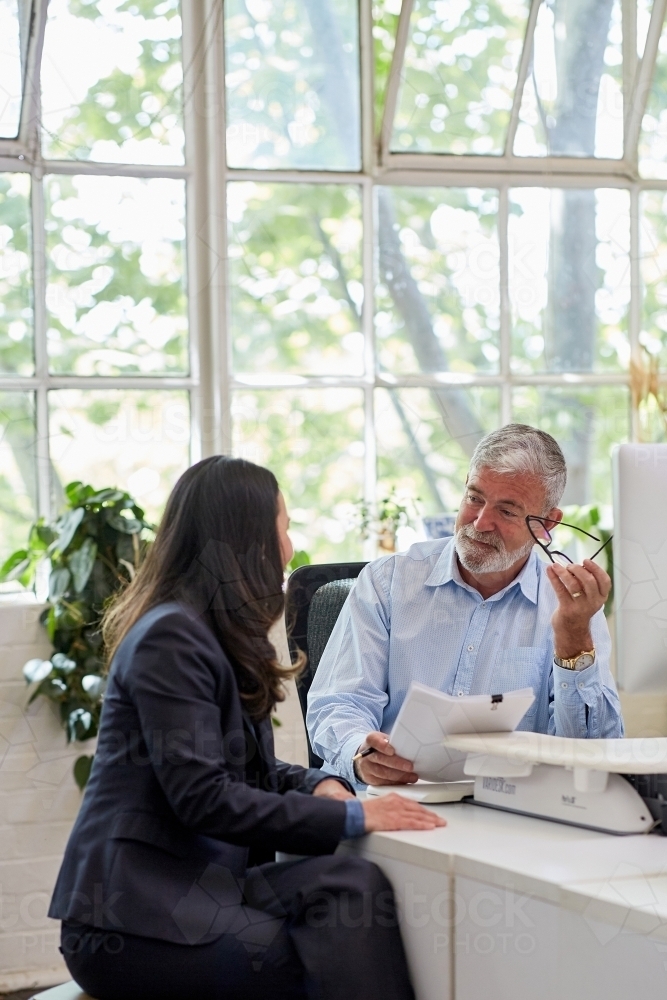Mature aged male office worker meeting with a woman in a creative warehouse space - Australian Stock Image
