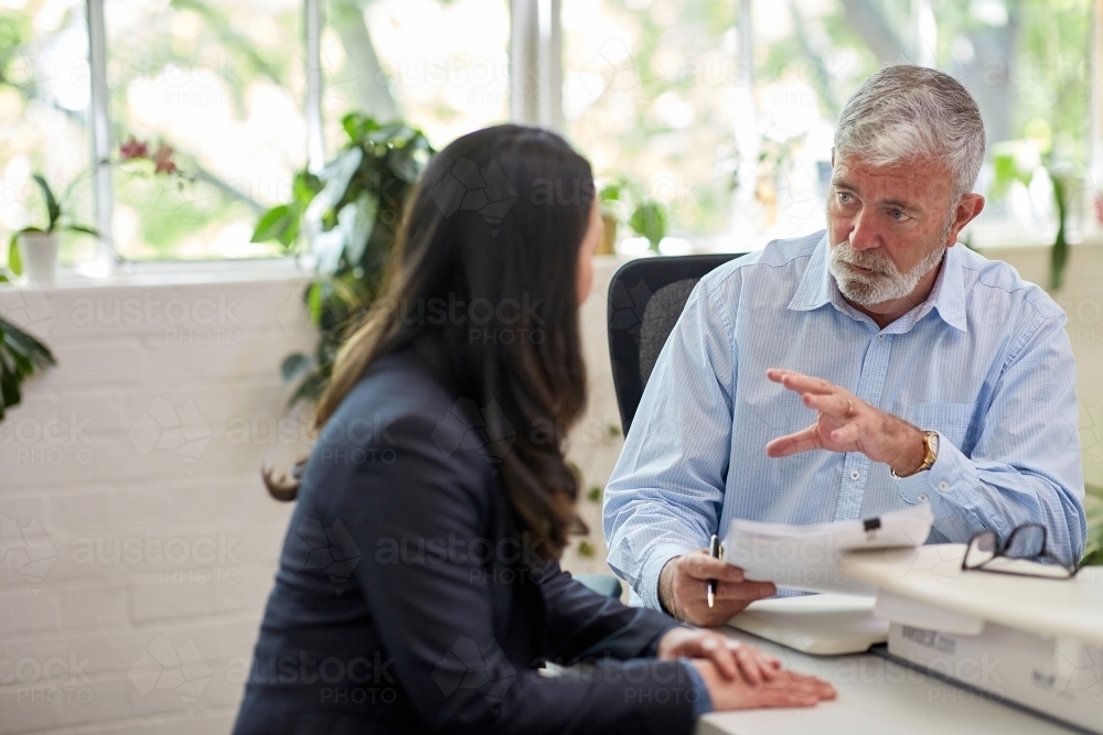 Mature aged male office worker meeting with a woman in a creative warehouse space - Australian Stock Image
