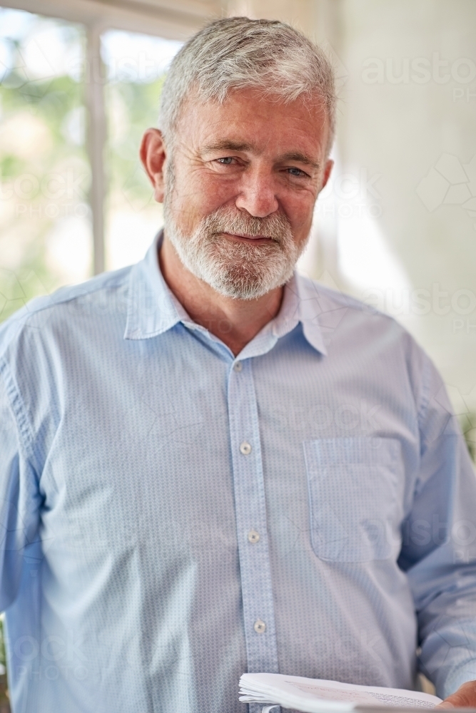 Mature business man holding files near a paned window - Australian Stock Image