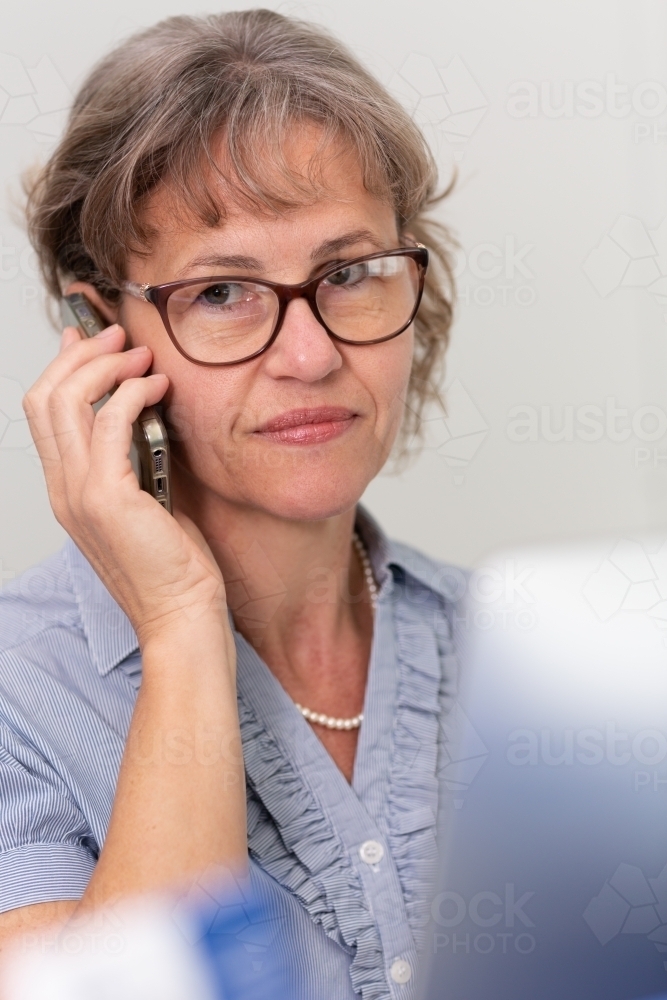 Mature business woman holding phone to ear - Australian Stock Image