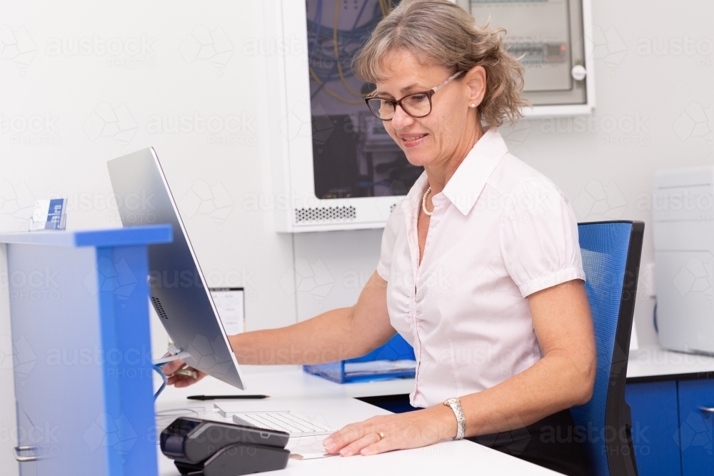 Mature lady office manager working at desk - Australian Stock Image