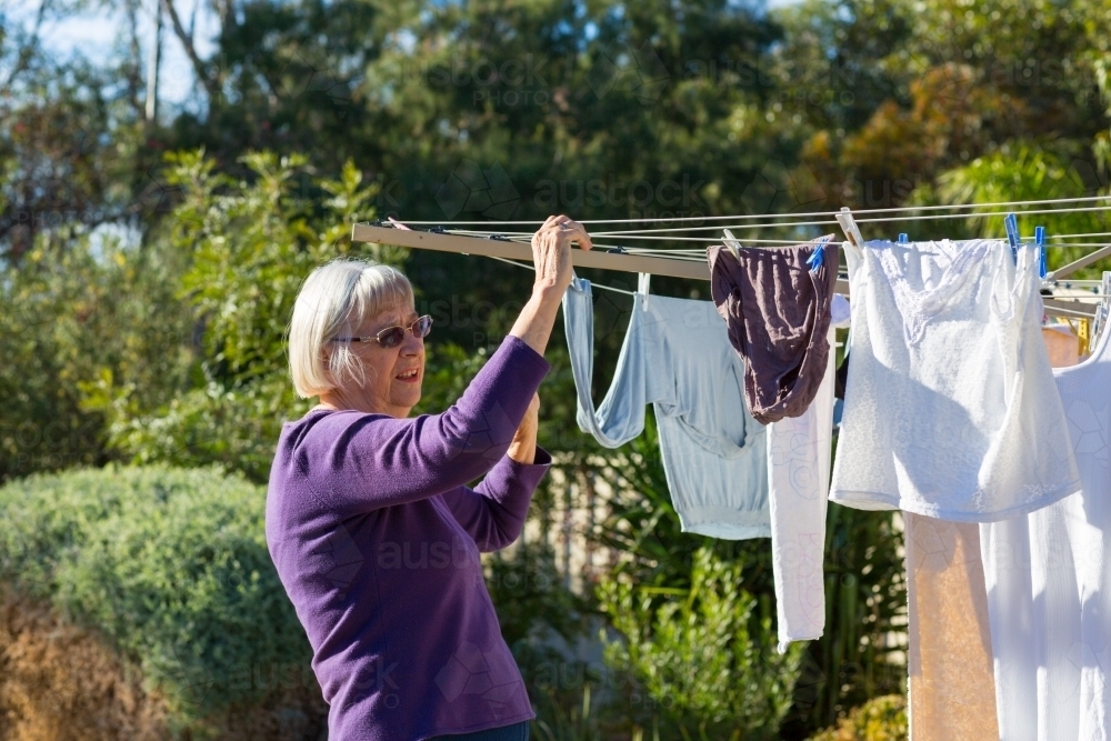 Mature lady taking laundry off clothesline - Australian Stock Image
