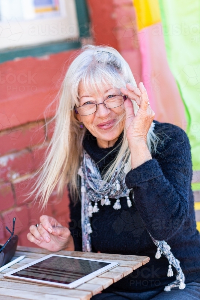 Mature lady wearing spectacles using tablet - Australian Stock Image