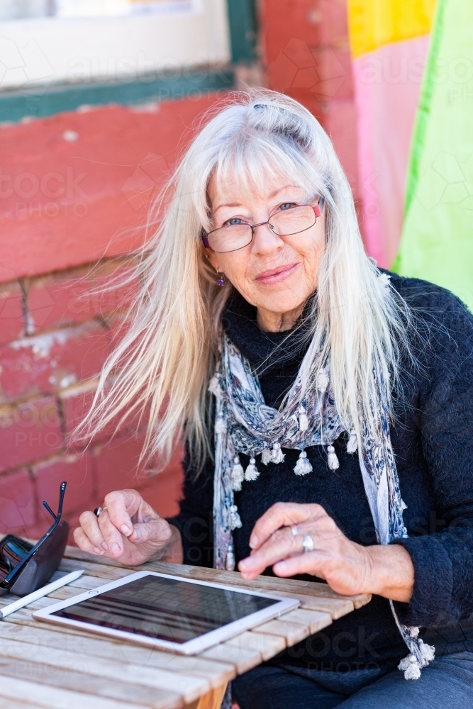 Mature lady wearing spectacles using tablet - Australian Stock Image
