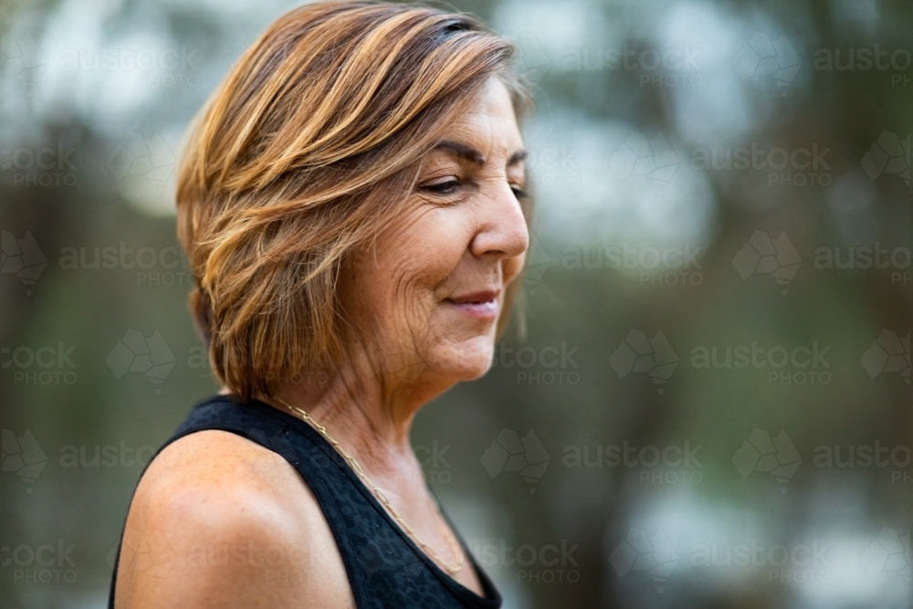 mature lady with coloured hair side-on with blurry background - Australian Stock Image