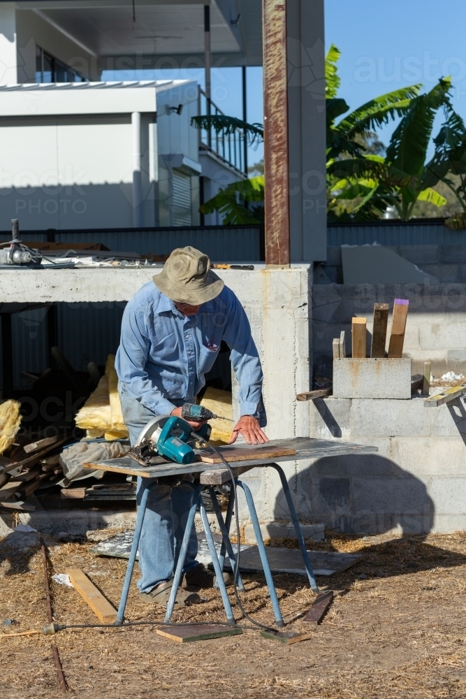 Mature man working with power tools on construction site - Australian Stock Image
