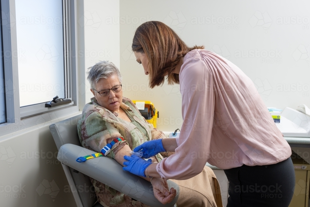 mature woman in phlebotomy chair with nurse taking blood test - Australian Stock Image