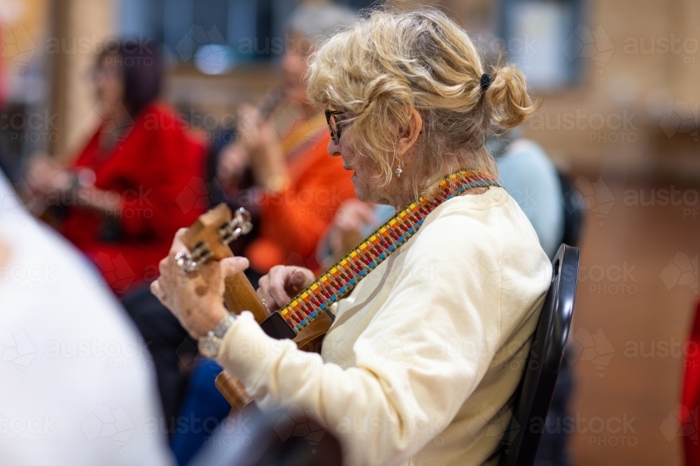 mature woman playing ukulele with a group - Australian Stock Image