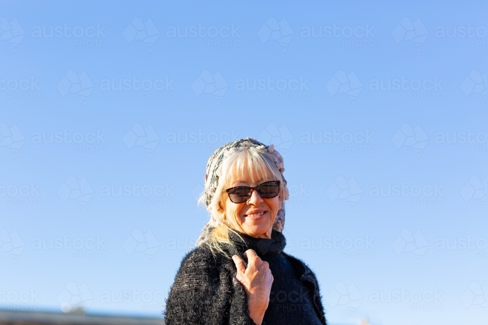 mature woman wearing sunglasses photographed against a blue sky - Australian Stock Image