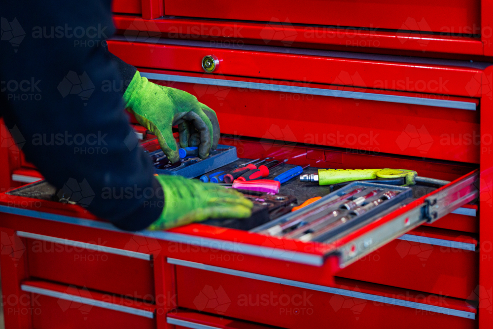Mechanics hand wearing gloves getting tools from the red tool chest - Australian Stock Image