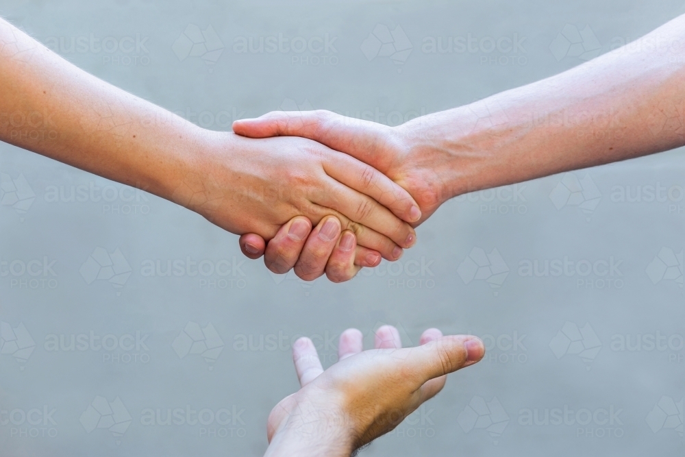 mediation concept - hands shaking in agreement with mediator - Australian Stock Image