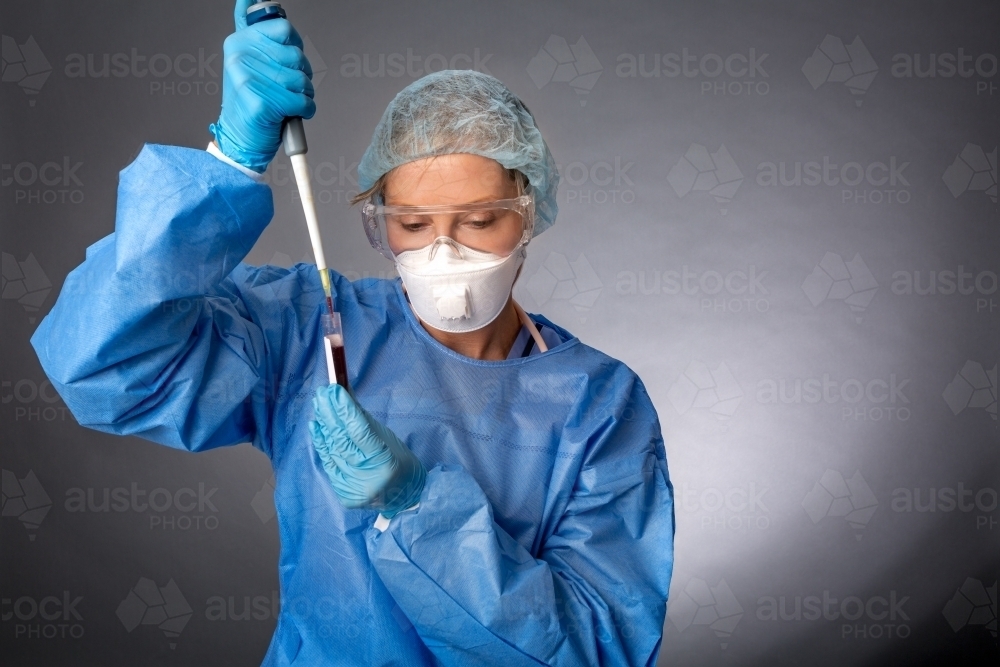 Medical laboratory worker using a pipette to sample blood test for analysis or research - Australian Stock Image