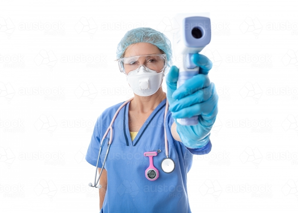 Medical nurse healthcare worker taking a temperature check for fever with infrared thermometer - Australian Stock Image