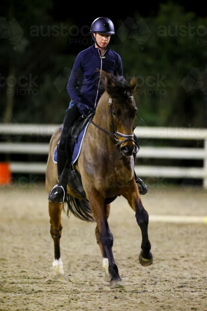 MELBOURNE, AUSTRALIA - July 26 2023: A female practices on her horse in an arena at night - Australian Stock Image