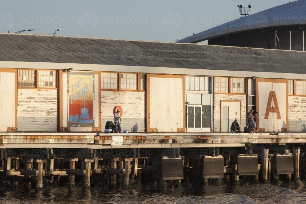 Men fishing near A Sheds at Fremantle Ports - Australian Stock Image
