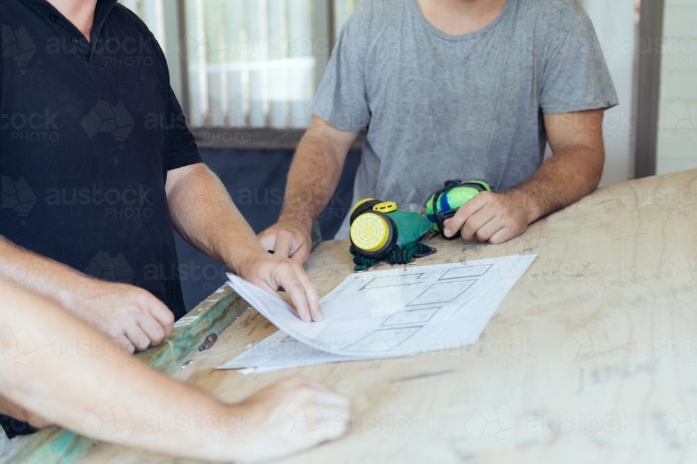 men overlooking plans on construction site - Australian Stock Image