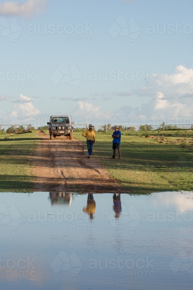 Men standing at edge of water - Australian Stock Image