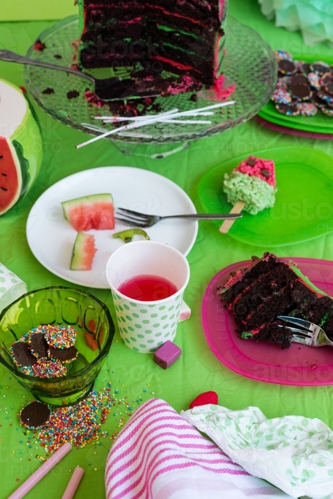 messy birthday party table, party food, candy covered chocolate, cake and fruit - Australian Stock Image