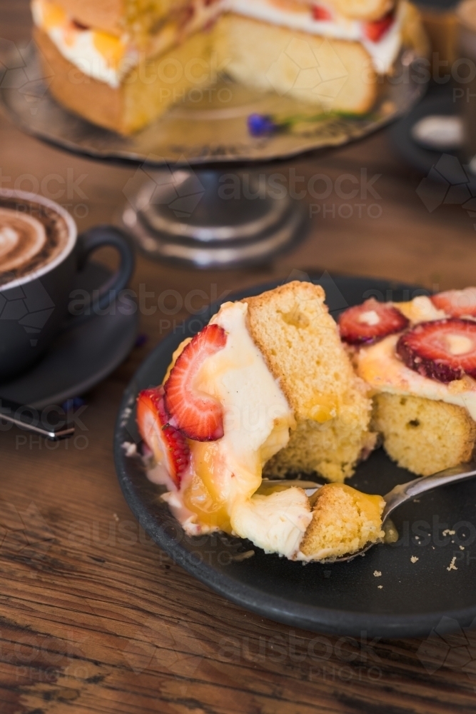 messy slice of sponge cake with lemon curd, strawberries and cream - Australian Stock Image