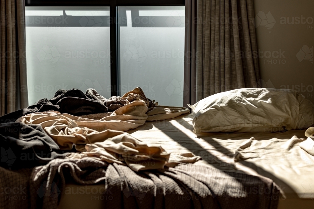 Messy unmade bed in the early morning - Australian Stock Image