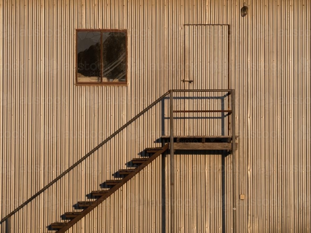 Metal steps on the side of a large corrugated building - Australian Stock Image