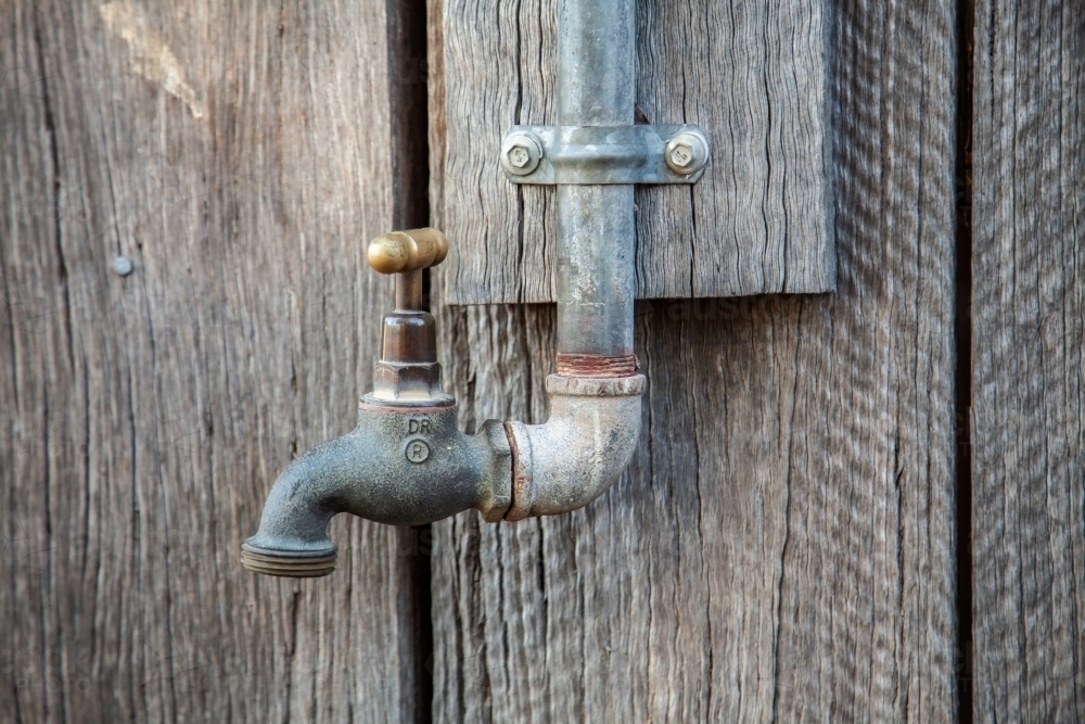 Metal tap fitting on side of wood shed - Australian Stock Image