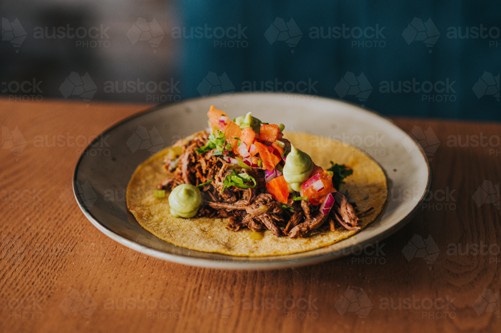 Mexican Taco With pulled Meat, Fresh Toppings, and Guacamole on Rustic Wooden Table - Australian Stock Image