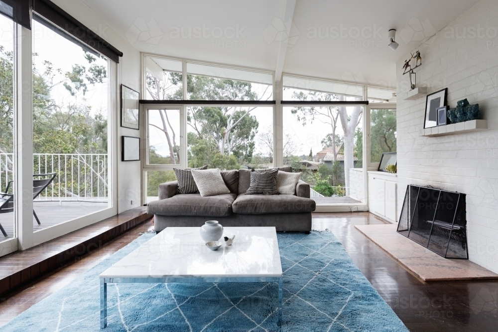 Mid century modern living room with huge windows to view the Australian treetops - Australian Stock Image