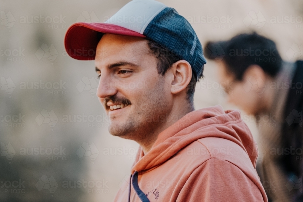 Mid twenties man in a cap smiles. - Australian Stock Image