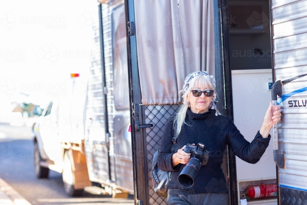 middle-aged lady traveller with camera at the caravan door - Australian Stock Image